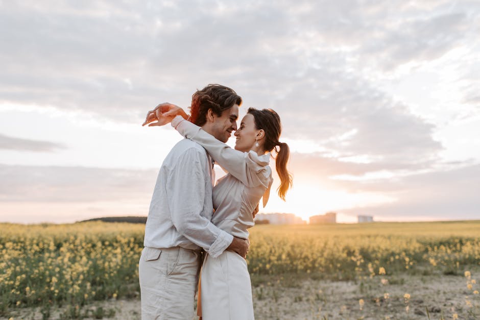 A romantic couple enjoys a tender embrace in a sunny flower field under a serene sky.