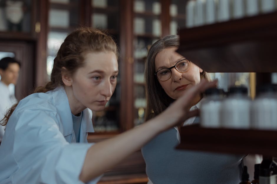 Two pharmacists wearing white coats and glasses examining medicine bottles on a pharmacy shelf.