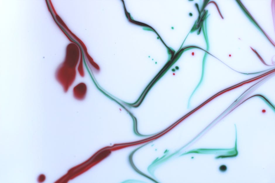 Abstract pattern with red and green ink flowing on a white background, showcasing fluidity and color contrast.
