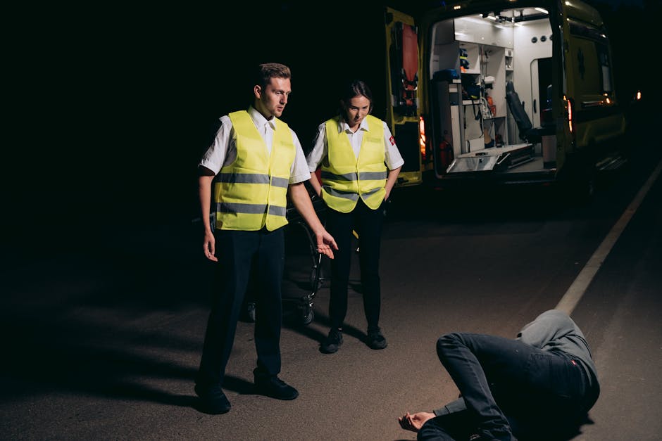 Paramedics assist a patient on a dimly lit street, showcasing emergency response at night.