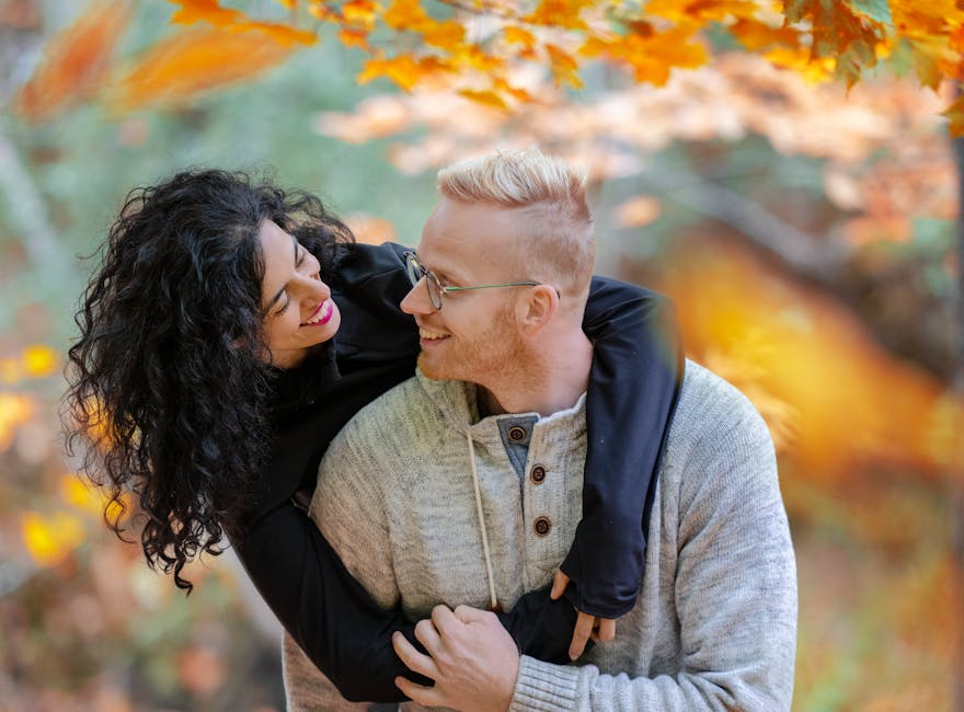 A cheerful couple enjoying a romantic moment in a fall park in Toronto, Canada.