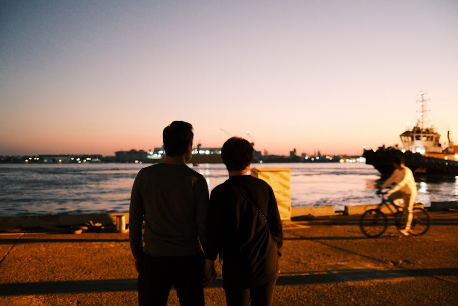 A couple stands by Kaohsiung Harbor at sunset, enjoying the serene view.