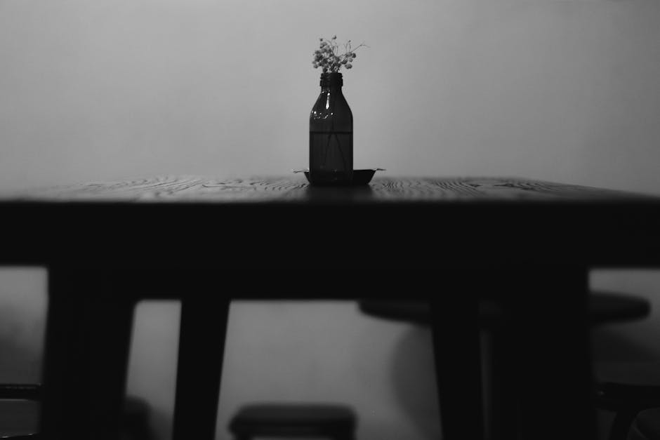 Stylish black and white photo of a vase on a wooden table, showcasing minimalist design.