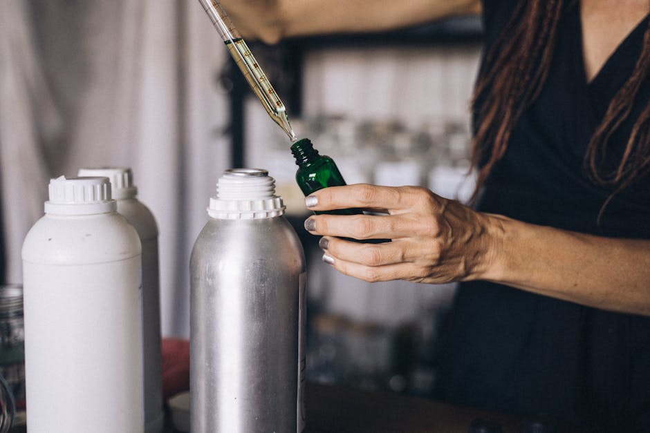 Woman using a dropper to prepare aromatherapy oils in an indoor setting.