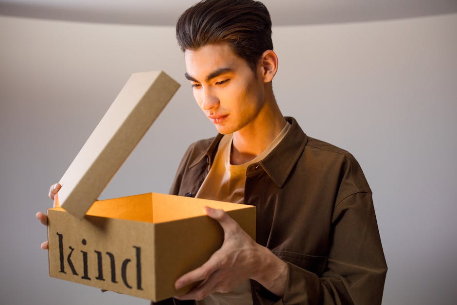 A man opens a cardboard box labeled 'kind' revealing a bright glow inside.