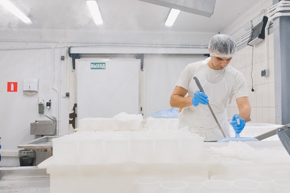 Man in sterile gear working in a cheese production facility, ensuring hygiene standards.