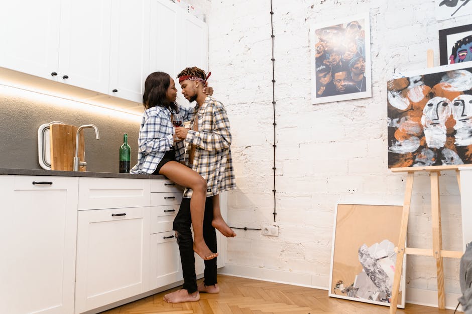 Affectionate couple enjoying a romantic moment in a modern kitchen surrounded by art.