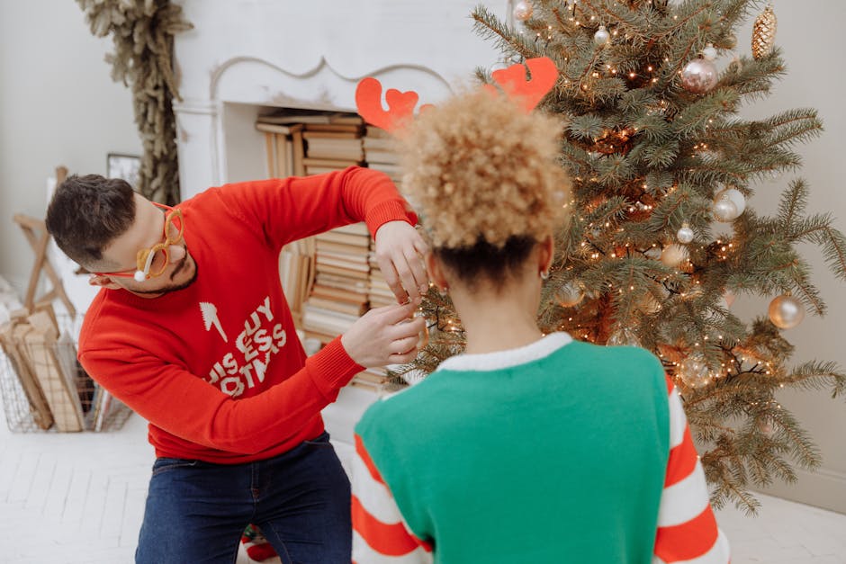Festive couple adding ornaments to a Christmas tree during holiday season indoors.