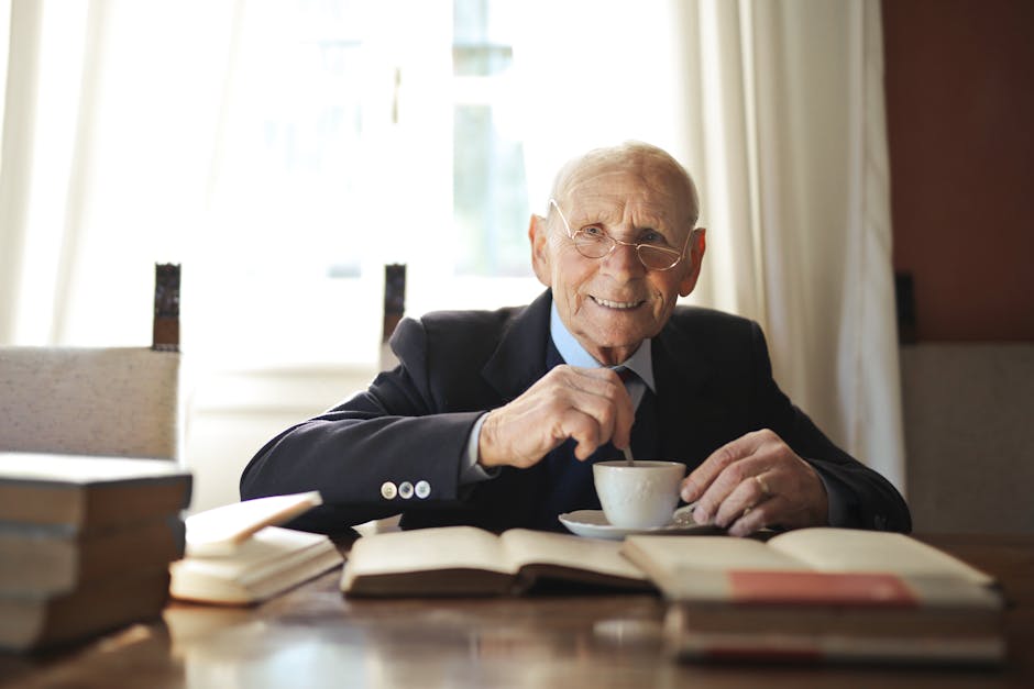 Senior man smiling while enjoying coffee in a cozy room surrounded by books.