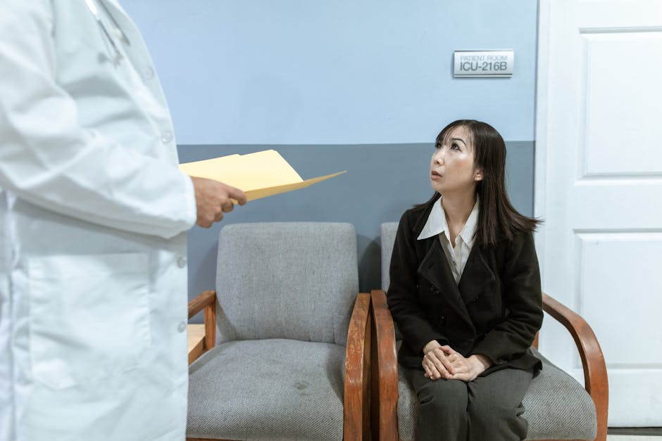 A worried woman seated in a hospital waiting room, interacting with a doctor.