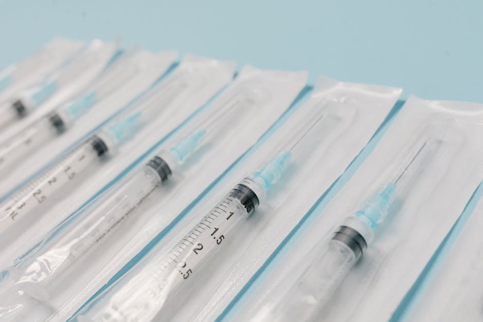 Close-up of sterile syringes aligned on a light blue surface, highlighting medical equipment.