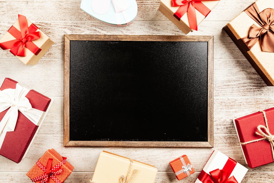 Flat lay of colorful gift boxes with ribbons surrounding a blank blackboard for holiday season messaging.