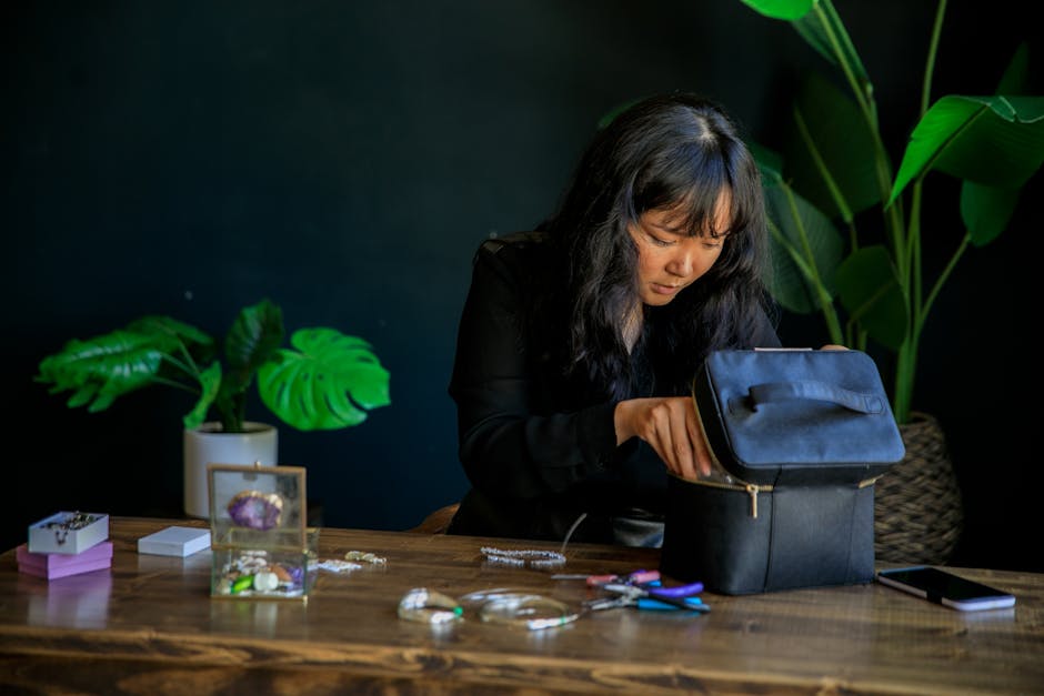 Woman searching through a box with jewelry on a wooden table indoors.