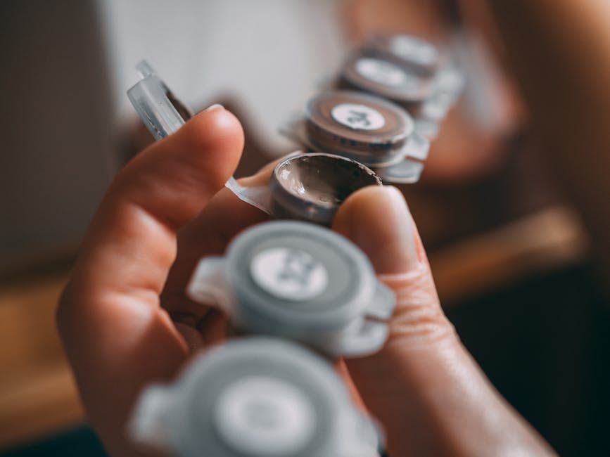 A close-up of a hand holding small paint containers, ready for creative artistry.