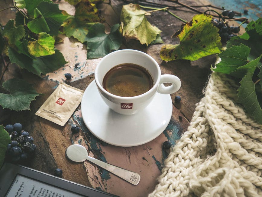 Autumn coffee setup with a cup, leaves, and blueberries on a rustic table.