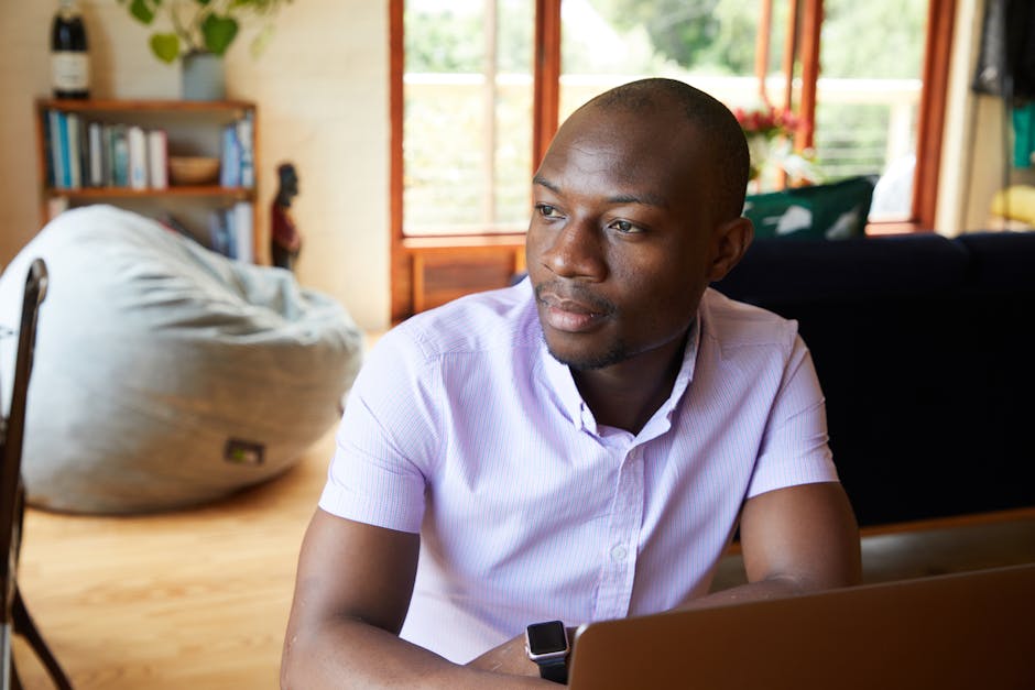 A young businessman reflecting while using a laptop at home.