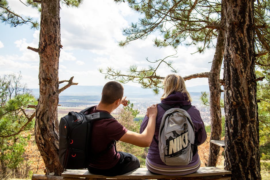 A couple enjoying a break on a forest bench with a scenic view, perfect for nature and lifestyle themes.
