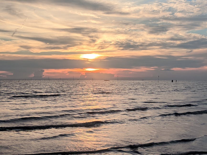 Peaceful ocean sunset with gentle waves and vibrant sky colors, perfect for a tranquil summer evening view.