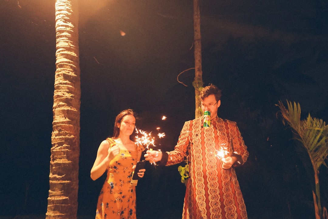 Couple holding sparklers with palm trees at night