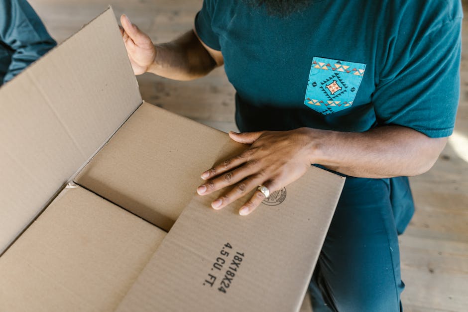 Close-up of a person opening a cardboard box indoors, highlighting hands and details.