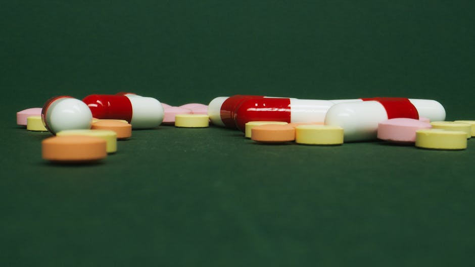 Close-up shot of colorful pills and capsules on a solid green surface.