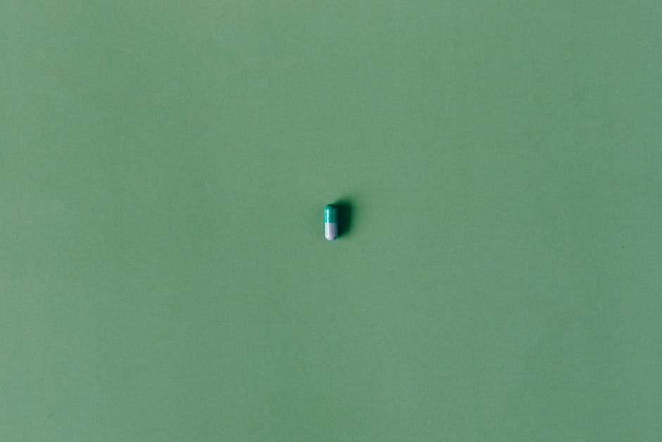 A single green capsule pill isolated against a matching solid green background.